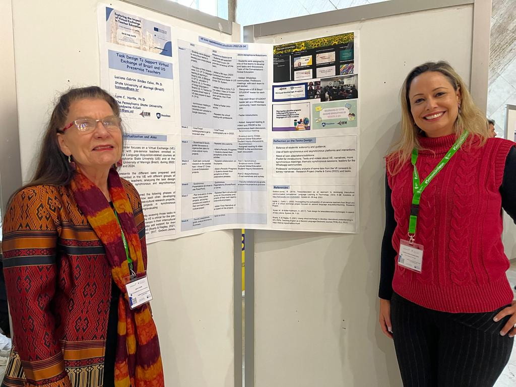 Dr. Lynn Hartle standing with her partner, Dr. Luciana Cabrini Simões Calvo in front of their poster presentation about their EDGE collaboration at the February 8-9, 2024, VALIANT conference in León, Spain.